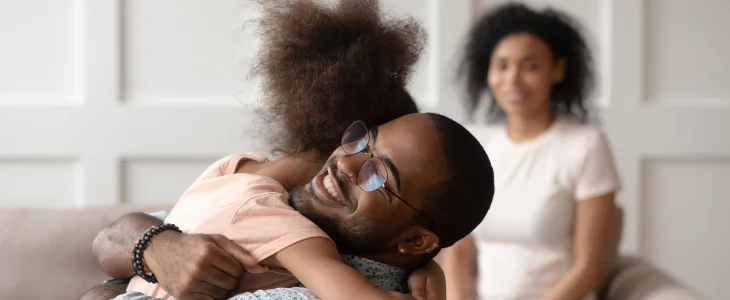 Father hugging his daughter with the mother in the background due to joint custody